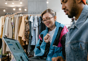 Woman and man working in a clothing store working on inventory management on a computer.