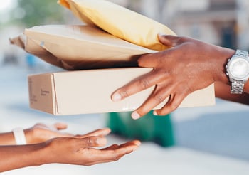 Person handing three packages to another person.