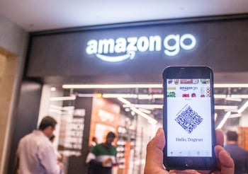 Person holding a smart phone with a QR code in front of an Amazon go store.