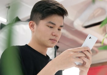 Man looking down at a white smartphone.