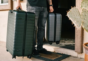 Person holding two rolling luggage bags.