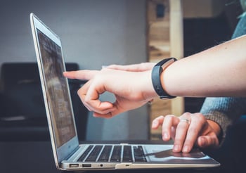 Two people pointing at a laptop screen.