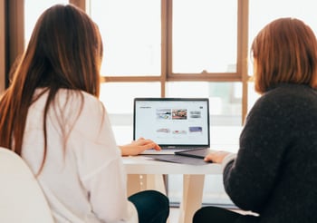 Two people creating content on a laptop.