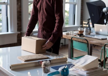 Person wrapping string around a cardboard box.