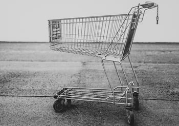 Chrome shopping cart on top of asphalt.