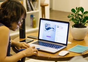 Person sitting at a round table working on a laptop computer.