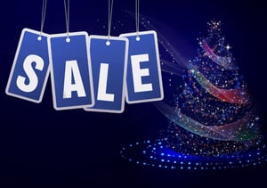 Decorative "SALE" sign hanging in front of a Christmas tree.