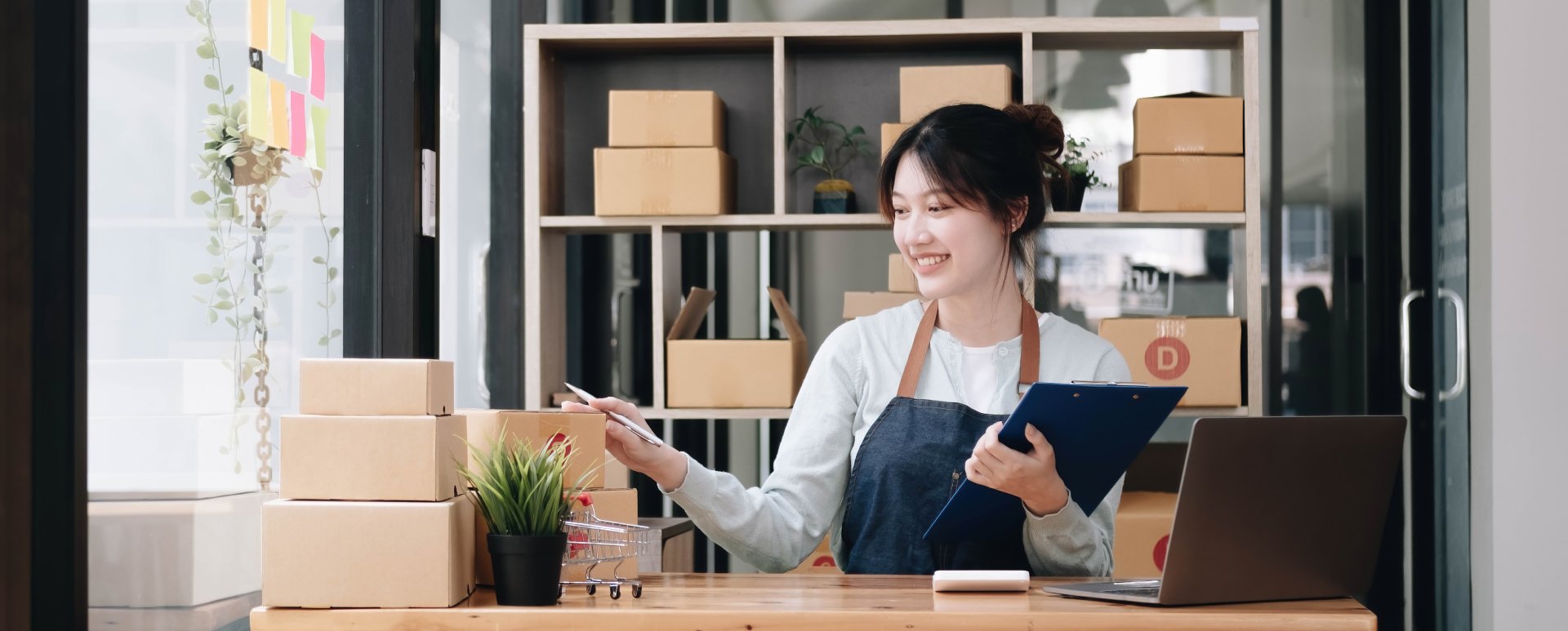 Woman holding a clipboard counting packing boxes on a countertop.