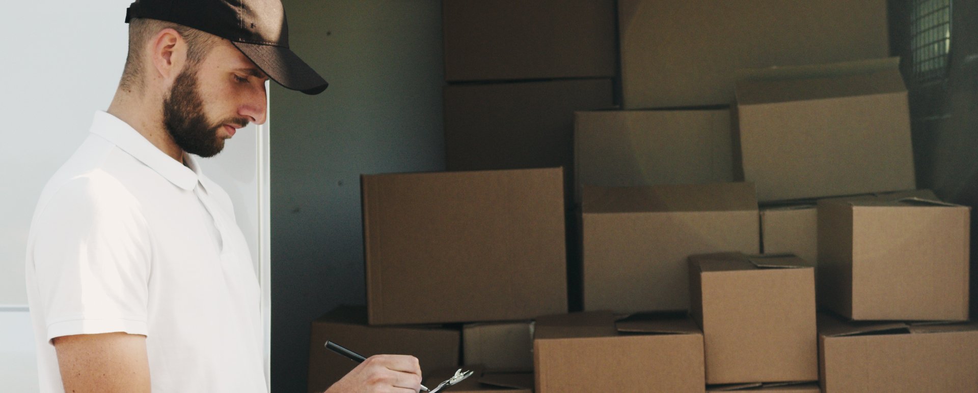 Man writing on a notepad standing in front of boxes.